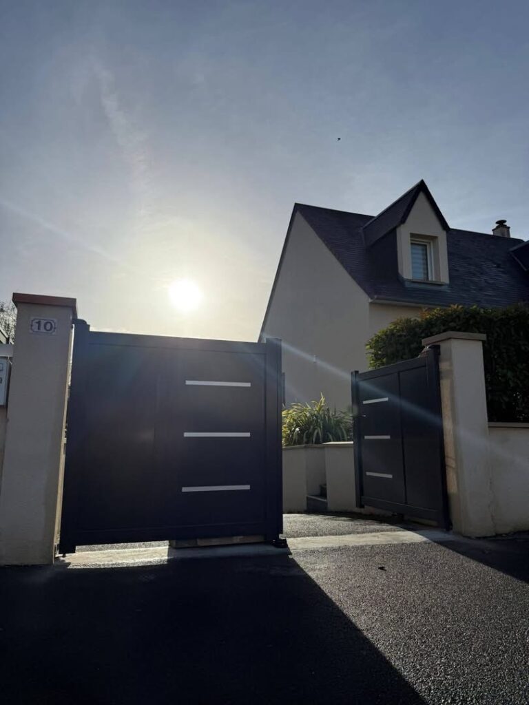 Menuiserie extérieure en Normandie : portail aluminium gris anthracite posé pour sécuriser l’accès d’une maison.
