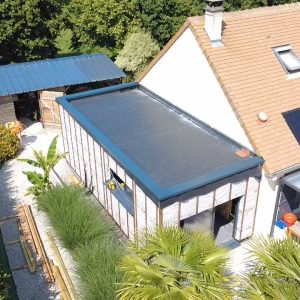 Isolation extérieure en Normandie : extension bardée gris anthracite avec toiture plate, vue aérienne.